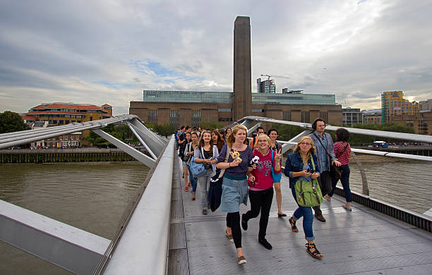 Tourists on Millennium Bridge London, UK - July 25, 2011: School excursion and other pedestrians on Millennium Bridge, with the Tate Museum of Modern Art in the background, in London on July 25, 2011 in London, UK field trip stock pictures, royalty-free photos & images