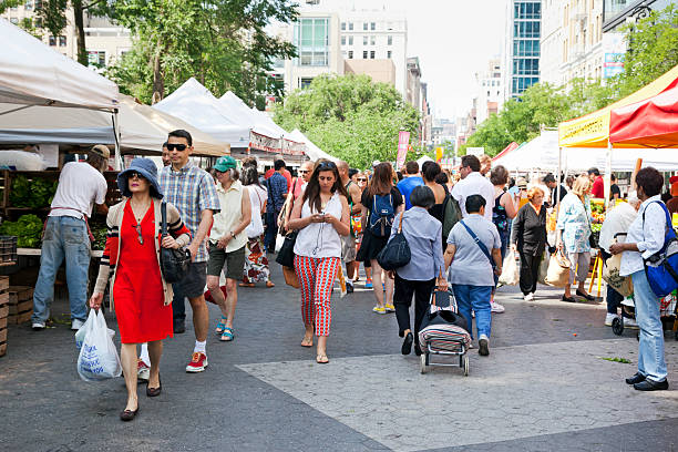 New York City, USA - June 22, 2013: People walking at the Union Square Greenmarket. This farmers market located in Union Square Park just above 14th street in New York City has been in existence since 1976. The world-famous Union Square Greenmarket began with a few farmers in 1976. Now in peak season, more than hundred regional farmers, fishermen, and bakers sell their products in Union Square.
