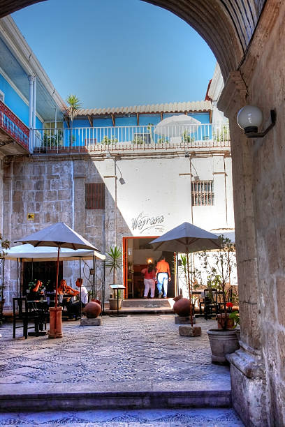 Arequipa, Peru - May 25, 2013: Restaurant entrance to courtyard on cobblestoned Peruvian street in Arequipa. People are pictured eating at the outside tables and a couple are entering the doorway