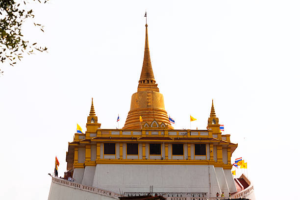 Bangkok, Thailand - February, 20th 2013: Golden Mountain of Bangkok in dust. Temple is seated on top of hill. Steps are leading around one way up and one way down. On top is golden pagoda and platform. On steps are some tourists.