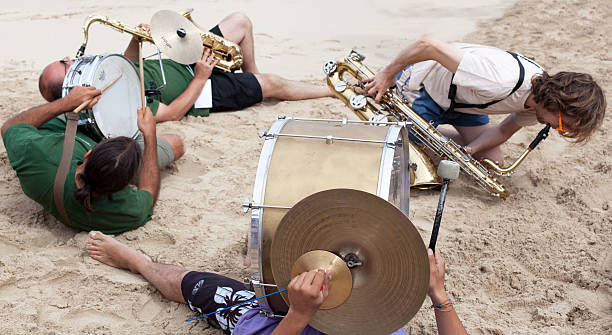 Santa Teresa Di Gallura, Italy - September 2, 2012: Italian Marching Band performing on the Beach of Rena Bianca. Four Male Musicians are playing drums and sax lying on the beach during the jazz festival 'Musica sulle Bocche'.