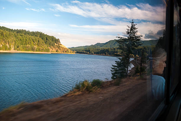 Roseburg, Oregon, USA - August 11, 2009: A female passenger is reflected in the window of a train as it speeds through scenic landscape in southwest Oregon, somewhere within a hundred miles of Roseburg.