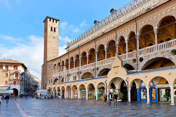 Padua, Italy - November 1, 2012: tourists walk along Palazzo della Ragione on Piazza delle Erbe. The Palazzo was begun in 1172 and finished in 1219 in Padova, Italy
