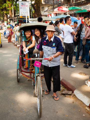 Mae Sai, Thailand - December 13, 2011: Rickshaw carrying asian passengers sets off to cross the border checkpoint at Mae Sai on the border between Thailand an Myanmar. The border area is busy with trade between the two countries, and particularly popular with Thai tourists looking for cheap goods.