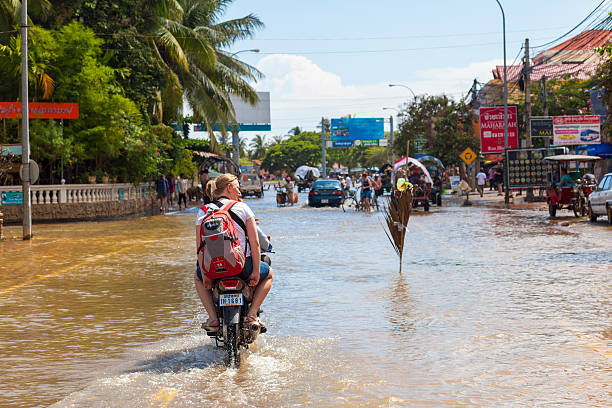 turista unità attraverso floodwaters a siem reap, cambogia - flood people asia cambodia foto e immagini stock