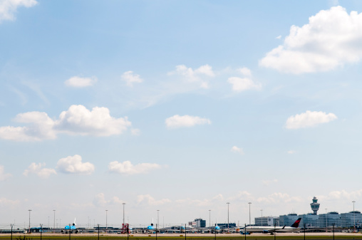 Schiphol, The Netherlands - June 12, 2011: Schiphol Airport on a summer's day. Various KLM planes and a Delta Airlines plane are parked on the tarmac behind a fence.