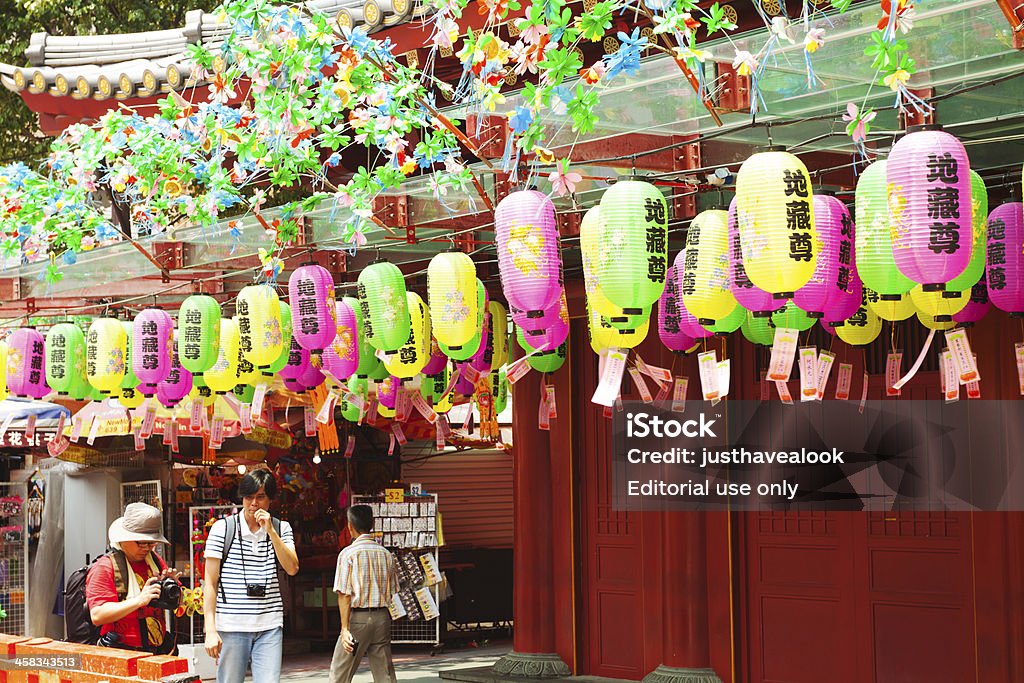 Chinese lanterns Singapore, Singapore - September, 4th 2012; Two Asian tourists and a man are walking along Buddha's Tooth and Relict temple in Chinatown of Singapore. Around temple is decoration with lanterns during midsummer festival. Both tourists are carring cameras. Adult Stock Photo