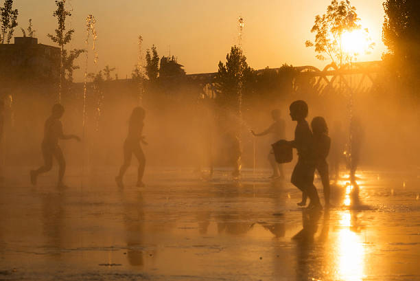 silhouetten der kinder spielen in einem brunnen in madrid - heat haze fotos stock-fotos und bilder