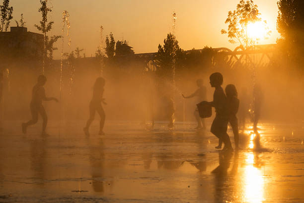Silhouettes of playful children in a fountain in Madrid Madrid, Spain - July 12, 2013: Young kids scape from the summer heat wave at dusk playing with the water jets in the fountains of the recently renovated Madrid RA-o park, by the Manzanares River in Madrid, Spain. heat wave photos stock pictures, royalty-free photos & images