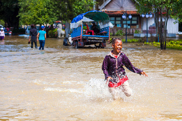 bambina corre attraverso floodwaters, siem reap, cambogia - flood people asia cambodia foto e immagini stock