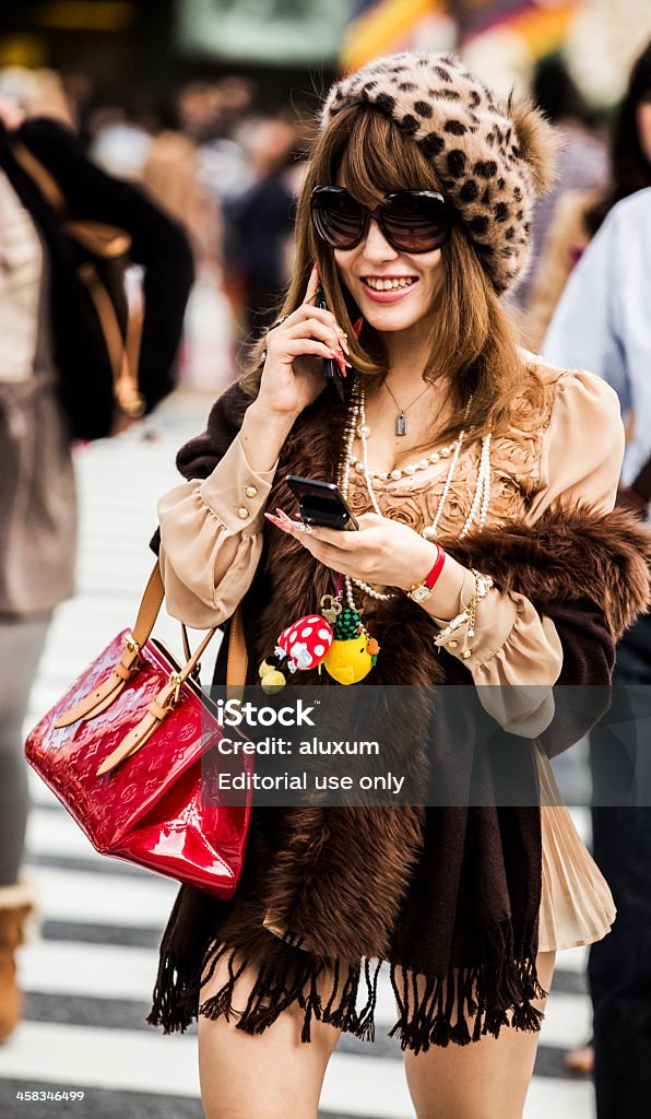 Elegant woman in Shibuya Tokyo Japan Tokyo, Japan - October 27, 2012: Beautiful young woman talking on the phone while crossing Shibuya Crossing in Tokyo Japan.With 15 square kilometer and a resident population of more than 200000 people it has become one of the best shopping districts of the city specially for young people. Shibuya is also worldly know by the scrambling crossing in front of the train station and it categorized as the busiest street crossing in the world. Purse Stock Photo