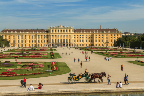 Vienna, Austria - September 10, 2012: Tourists visiting the magnificent gardens of Schonbrunn Palace, one of the most significant cultural and naturalistic landmarks not only in Vienna but in the whole Austria. A horse-drawn carriage takes a sightseeing tour.