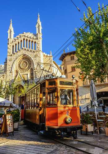Soller, Majorca, Spain - April 13, 2013: The historic tram of Soller is passing the Sant Bartomeu church and main square of Soller on a beautiful spring evening. 