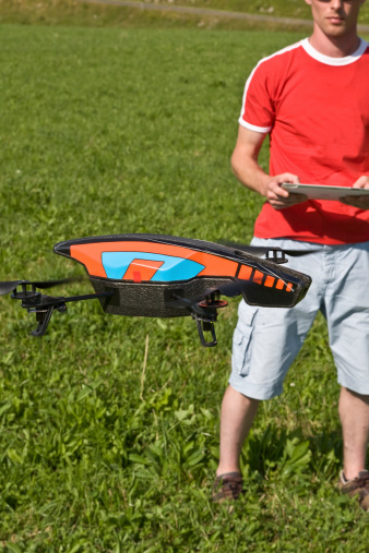 Heuteville Lompnes, France - August 15, 2013: a man playing with a Drone, quadricopter toy, controlled by Apple interface.