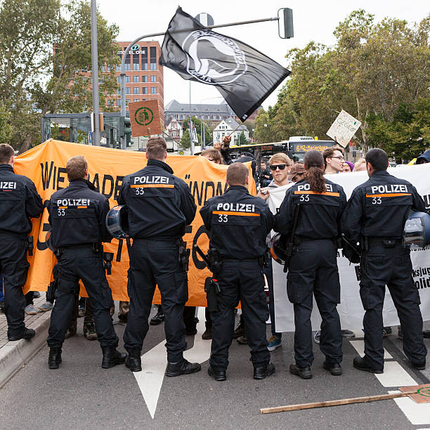 Protests against NPD election campaign Wiesbaden, Germany - August 26, 2013: Counterprotestors against a NPD election campaign speech in the city center of Wiesbaden. In the foreground a riot police cordon trying to separate Nazis and protestors from each other. Founded in 1964 the NPD is a German nationalist party, its agitation is racist, antisemitic and revisionist. national democratic party of germany stock pictures, royalty-free photos & images