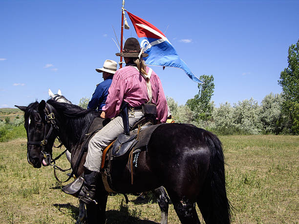 Crow Agency, Montana USA - June 27, 2009: Reenactment of the Battle of the Little Bighorn known as Custer's Last Stand. Indian scout rides with U.S. 7th Cavalry soldier carrying the Cavalry flag.