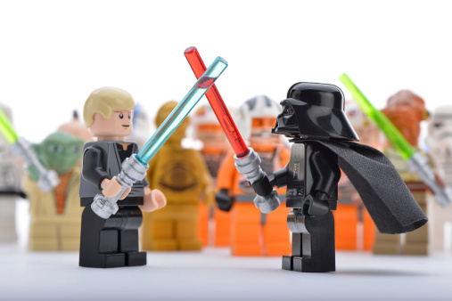 Ankara, Turkey - April 06, 2013: Lego Star Wars minifigure Darth Vader and Luke Skywalker are fighting with sword in front of other Star Wars characters isolated on white background.