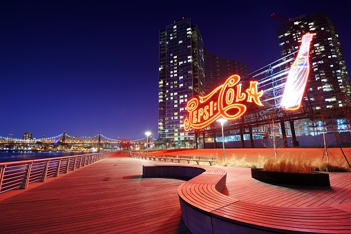 New York, USA - April 5, 2013: The Pepsi-Cola sign at Gantry Plaza State Park illuminates the riverfront promenade. Opened as a park in sections beginning in 1998, the northern section was formerly a Pepsi Bottling Plant.
