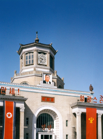 Pyongyang, North Korea - July 4, 2005: the sun illuminates the Central Train Station facade with a portrait of Kim Il-Sung