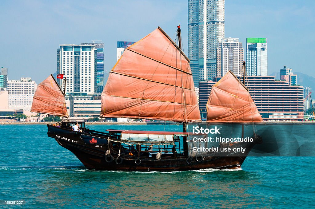 Traditional Chinese Junkboat sailing across Hong Kong Harbour Hong Kong, Hong Kong - November 16, 2013: Traditional Chinese Junkboat sailing across Victoria Harbour, Hong Kong, tourist can take a ride on board for a round trip, background is the Tsim Sha Tsui of Kowloon. Asia Stock Photo