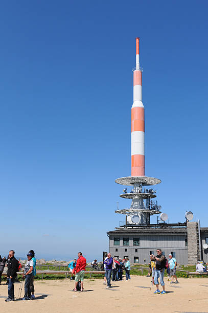Peak of Brocken Mountain at Harz National Park (Germany) Brocken, Germany - May 26, 2012: Peak of Brocken Mountain at Harz National Park (Saxony-anhalt, Germany) with its typical red white communication tower and the Hotel at Brocken with two restaurants. In front a group of hiking people walking around on peak. sendemast stock pictures, royalty-free photos & images