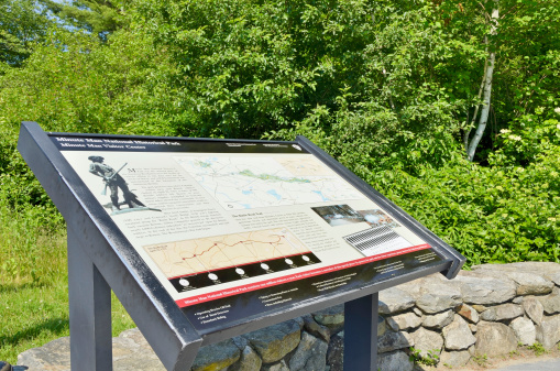 Lexington, Massachusetts, USA - June 10, 2012: A sign with illustrations explains the timeline and significance of events of the American Revolution at the Minuteman National Historic Park.