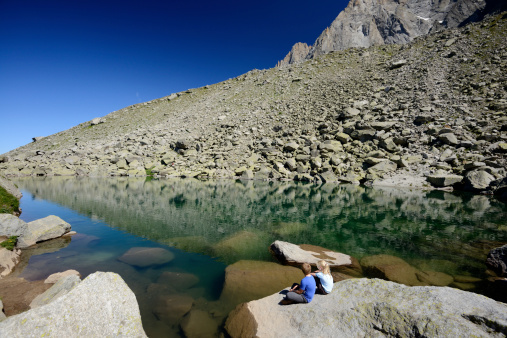 Chamonix, France - August 20, 2013: Two kids, brother and sister, watching the beautiful Lac Bleu (Blue Lake), near the Plan de Aiguille du Middi in summer season .  Nobody else in the picture.