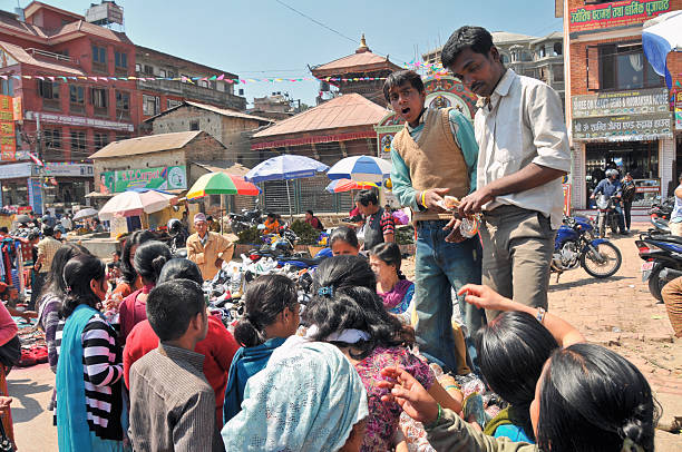 Kathmandu, Nepal - March 12, 2011: Two Nepali boys selling bracelets on the street market next to the Pashupatinath temple in Kathmandu, Nepal. Many young people around them buying items.