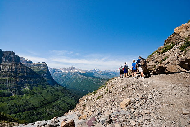 Hikers on a Narrow Ledge Glacier National Park, Montana, USA - August 14, 2013: This group of hikers, on the Highline Trail, makes their way across a narrow ledge below the Continental Divide in the Rocky Mountains. jeff goulden glacier national park stock pictures, royalty-free photos & images