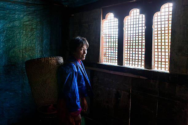 Bhutanese donna guardando Thangbi festività dall'interno della sua casa - foto stock