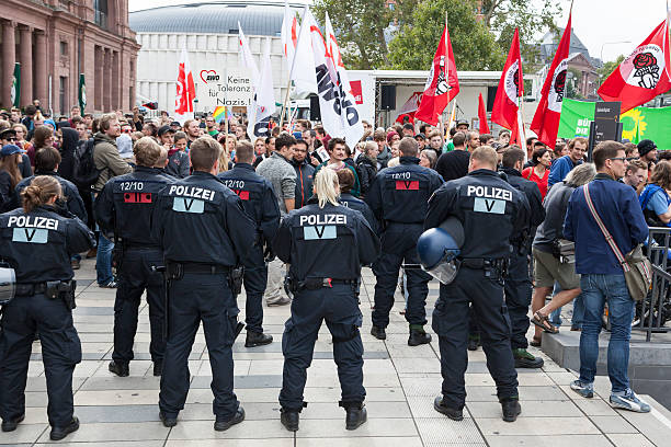 Protests against NPD election campaign Wiesbaden, Germany - August 26, 2013: Counterprotestors against a NPD election campaign speech in the city center of Wiesbaden. In the foreground a riot police cordon trying to separate Nazis and protestors from each other. Founded in 1964 the NPD is a German nationalist party, its agitation is racist, antisemitic and revisionist. national democratic party of germany stock pictures, royalty-free photos & images