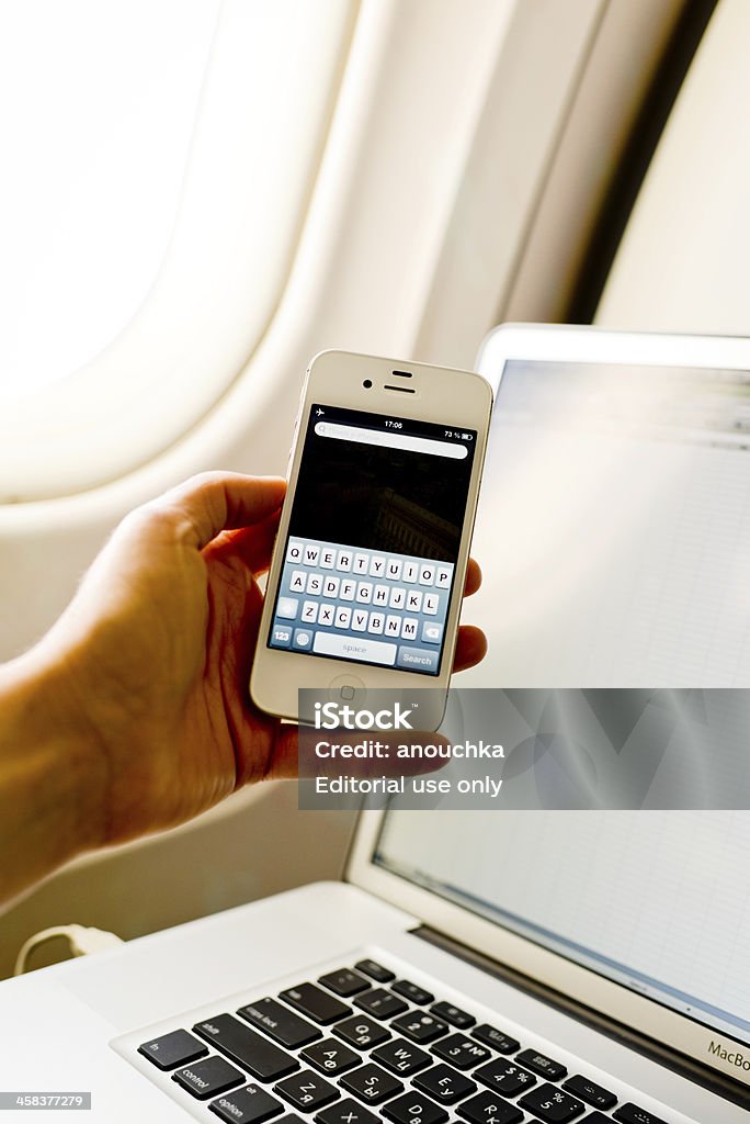 Mulher usando um iPhone 4s e laptop no avião durante o voo - Foto de stock de A caminho royalty-free
