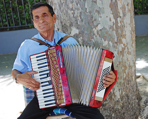 The accordion master Madrid, Spain- June 07, 2013: A senior man looking calm and serene  playing his accordion in a public park in central Madrid. klezmer stock pictures, royalty-free photos & images