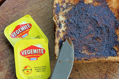 Reichenbach, Germany - 0ctober 4, 2013: Vegemite on Toast - Produce in Australia at Kraft Foods' Port Melbourne. It's a popular dark brown australian Food Paste - used as spread for sandwiches and toast - the Australian People love it for Breakfast. It taste similar to beef bouillon. I shot this photo at home in Germany - the Vegemite was a Souvenir from my Australia Trip. Toast with Knife and 2 small packages of Vegemite.