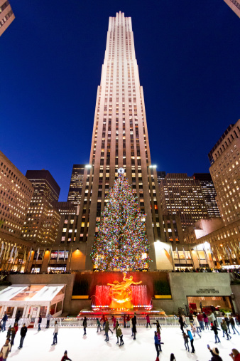 New York City, US - December 13, 2012: Ice skaters on the ice rink at Rockefeller Center with the famous Christmas tree. Rockefeller is a landmark complex of buildings located in the middle of Manhattan and it's popular destination for New Yorkers as well as visitors.