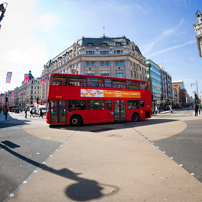 London, England, UK - May 4, 2011: a typical red bus drives in Oxford Circus in the city of London during a bright spring day. Photo taken with a fish-eye lens.
