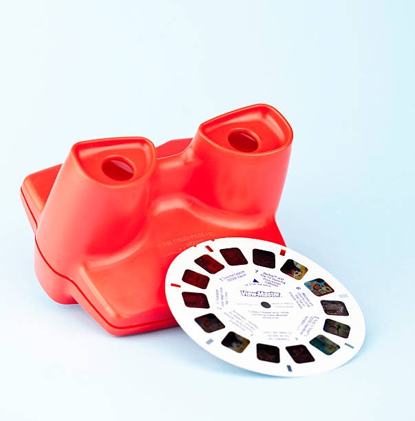 Viewmaster Toy Suffolk, Virginia, USA - April 30, 2011: A square format studio shot of a red Fisher-Price 3D Viewmaster Viewer with one film reel resting against it. view finder stock pictures, royalty-free photos & images