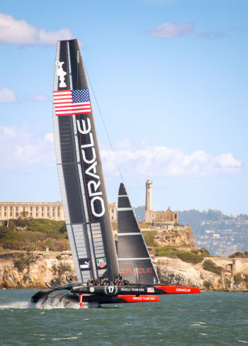 San Francisco, CA, USA aa September 25, 2013: The Oracle Team USA AC72 catamaran rides on foils above the water of San Francisco Bay past the landmark Alcatraz Island as it races toward victory in the final America's Cup race. In one of the greatest comeback stories in the history of sports, Oracle Team USA, down 8-1 to Emirates New Zealand, scored eight consecutive wins to defeat New Zealand 9-8 and win the 34th America's Cup.