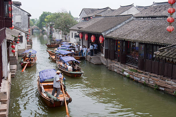 Water Town Zhouzhuang, China Zhouzhuang, China - July, 15th 2007 : Villagers row boats at a canal, many tourists go sightseeing on the boats in Zhouzhuang Town of Kunshan City, Jiangsu Province, China. Zhouzhuang, first built around 1,000 years ago, is one of the most famous water townships in China, noted for its profound cultural background, the well preserved ancient residential houses, the elegant watery views and the colourful local traditions and folklore. Sixty percent of Zhouzhuang\\\'s structures were built during the Ming and Qing Dynasties from 1368 to 1911. grand canal china stock pictures, royalty-free photos & images