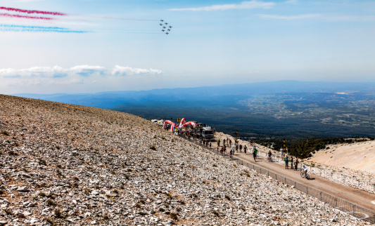 Mont Ventoux, France- July 14 2013: Planes formation fly above the Mount Ventoux while people rise up the last kilometer mark of the climbing route to the top in the stage 15 of the 100 edition of Le Tour de France 2013. 14 July is the France National day.
