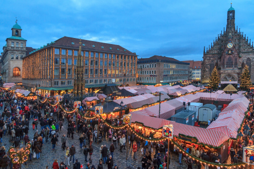 Nuremberg, Germany - December 15, 2012: People strolling in the large Hauptplatz, in downtown Nuremberg, full of market stalls covered by the characteristic awnings in red and white stripes. This Christmas market of Nuremberg is one of the Germany's oldest Christmas fairs.
