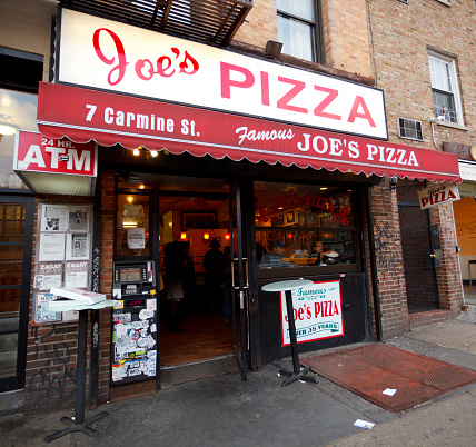 New York, New York, USA - March 13, 2011: Joe\\'s Pizza on Carmine Street in Greenwich Village New York City. This is a small but well known pizza establishment in New York. They are known for good pizza as well as being in the movie Spiderman 2 (although they were located a few doors down at the time). People can be seen inside ordering and eating pizza.