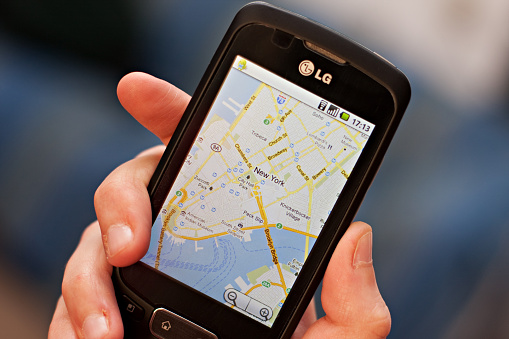 Milan, Italy - May 8, 2011: Hand holding a smartphone with screen showing the Google maps app, satellite view of New York City . The smartphone is an Lg optimus one P500. The operating system is Android 2.2. developed by Google.