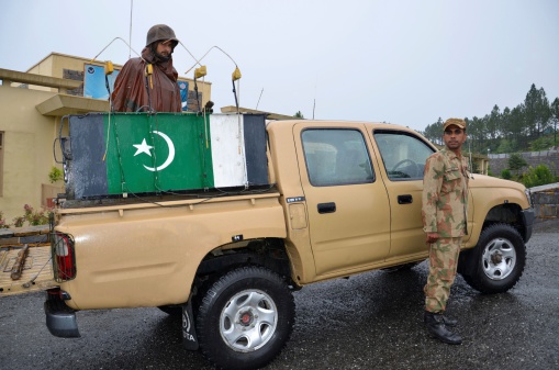 Swat Valley, North Pakistan - September 17, 2012: Pakistani military soldiers alongside a military pick-up truck outside a base in the Swat Valley, Pakistan.