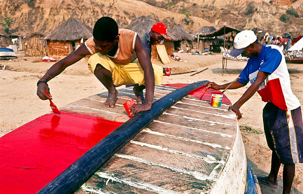 Cabo Ledo, Bengo Province, Angola aa August 16, 2003: Men painting boat in fishing village.