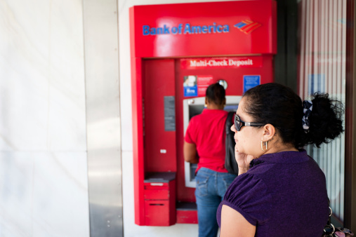 Miami, Florida, United States - March 19, 2011: Latin woman talking at the phone, while queueing at the atm of Bank of America in Miami, Florida, USA.