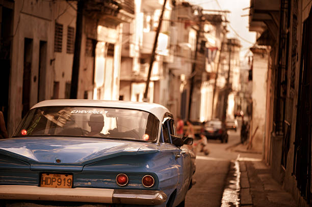 Havana, Cuba - January 3, 2011: Blue classic Chevrolet driving down a narrow one-way street of old Havana in the evening