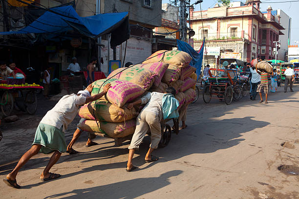 New Delhi, India - September 22, 2013.  Indian porters struggle to push a cart loaded with more than a 500 kilos of dried chili peppers through the streets of the old part of the city.