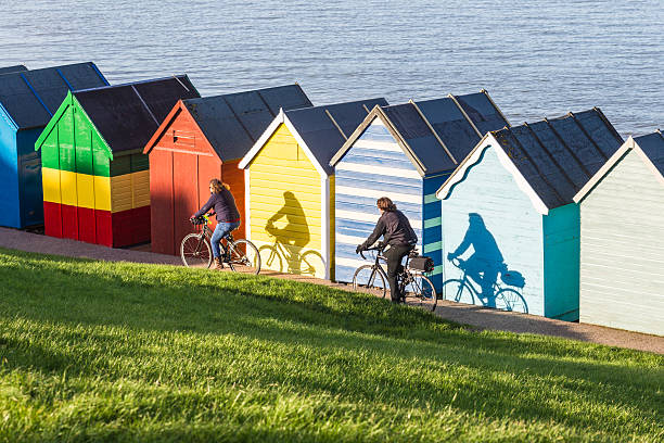 Winter Sunshine Kent, UK - November 16th, 2013: Cyclists cast their shadows on the quaint colorful beach huts of Herne Bay on a rare sunny day in November. herne bay photos stock pictures, royalty-free photos & images
