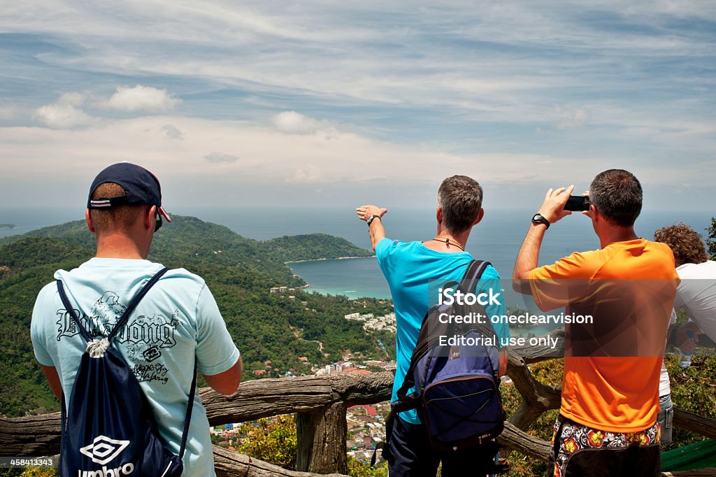 Tourist View Phuket, Thailand - April 25, 2011: Three men look out over a view from a high point on Phuket island, Thailand. Tourism is a main source of income on Phuket Island. Adult Stock Photo